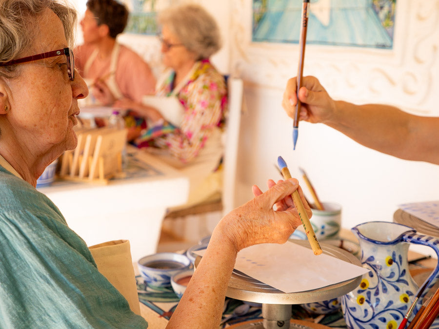 Person assisting another person with a painting activity in a casual setting.