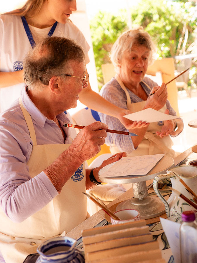 Group of people, including an elderly couple, engaged in a painting activity outdoors.